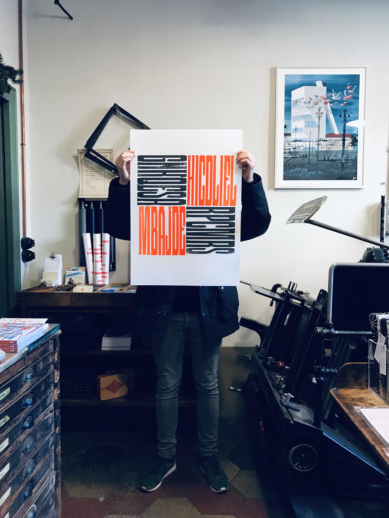 man holding a letterpress poster in a printing workshop